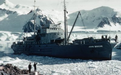 A large ship in the water with a mountain in the snow.