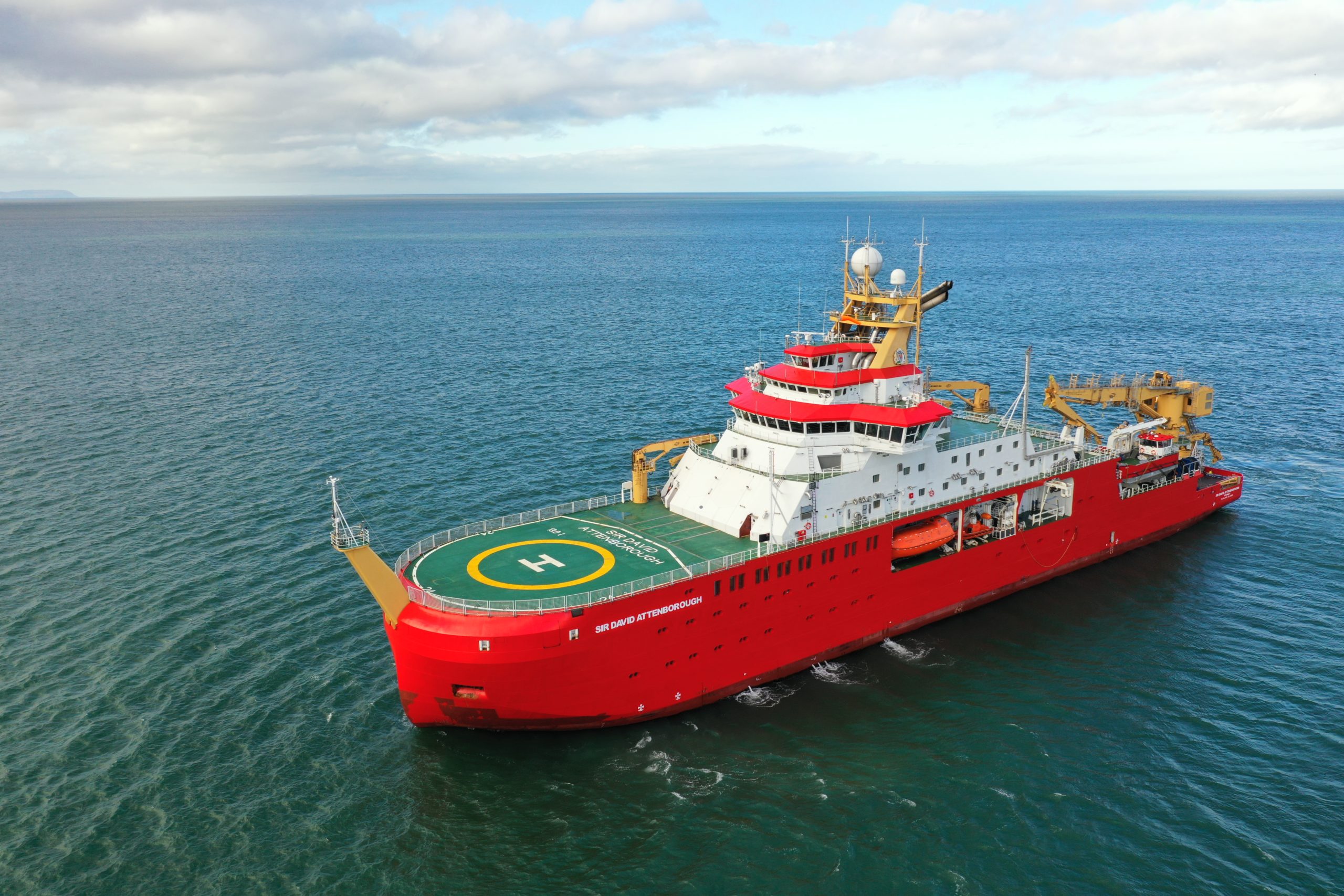 A large red ship with a green deck, sideways on, in the ocean