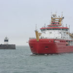 Large red ship arrives into a port