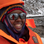 A person wearing a hard hat and sunglasses posing for the camera